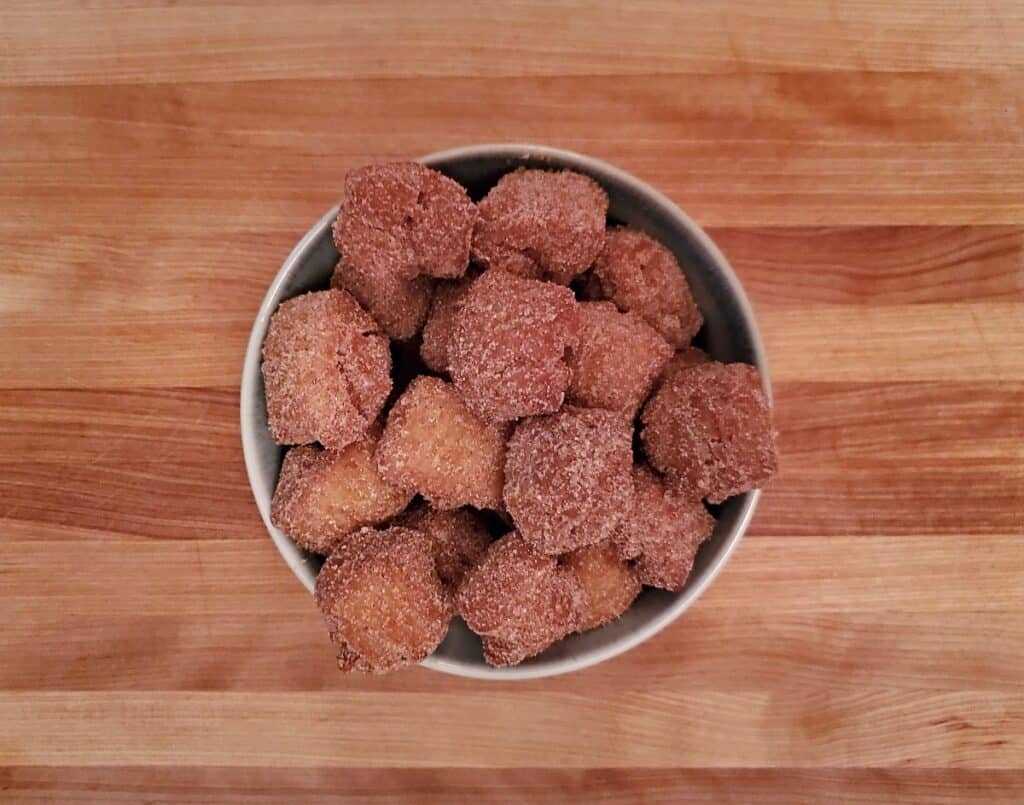 Bowl of pumpkin donut holes on a wooden table.
