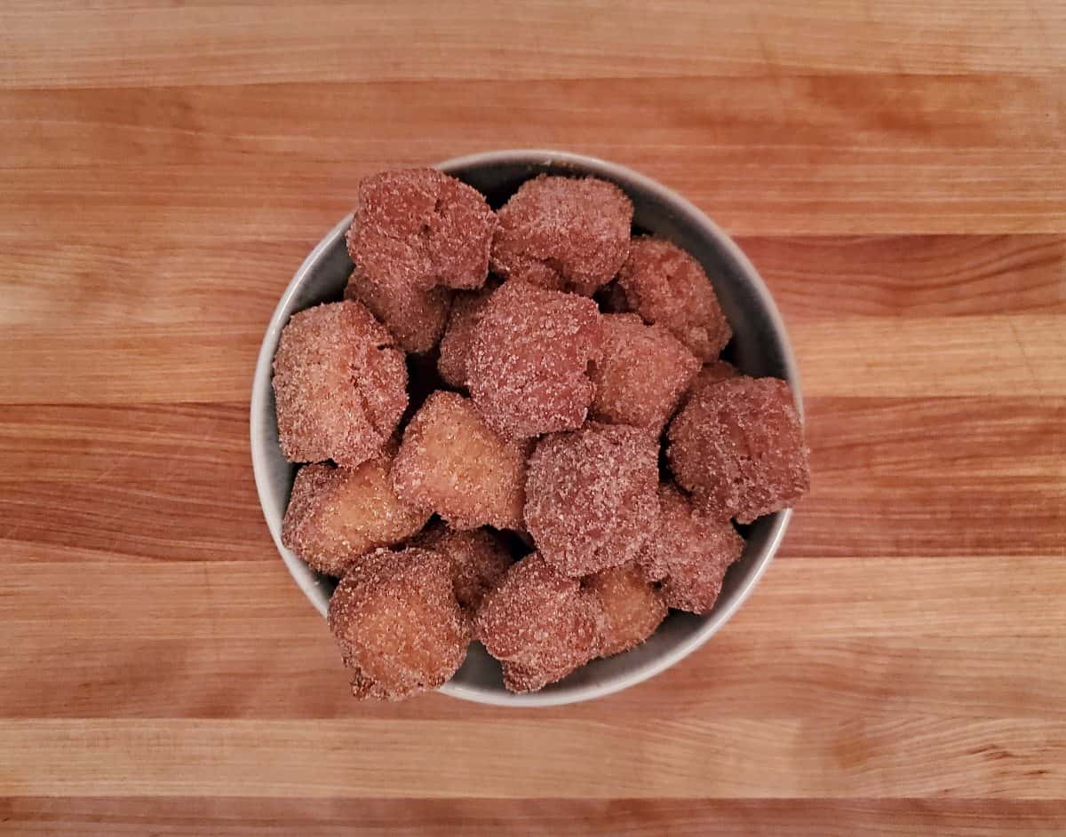 Bowl of pumpkin donut holes on a wooden table.