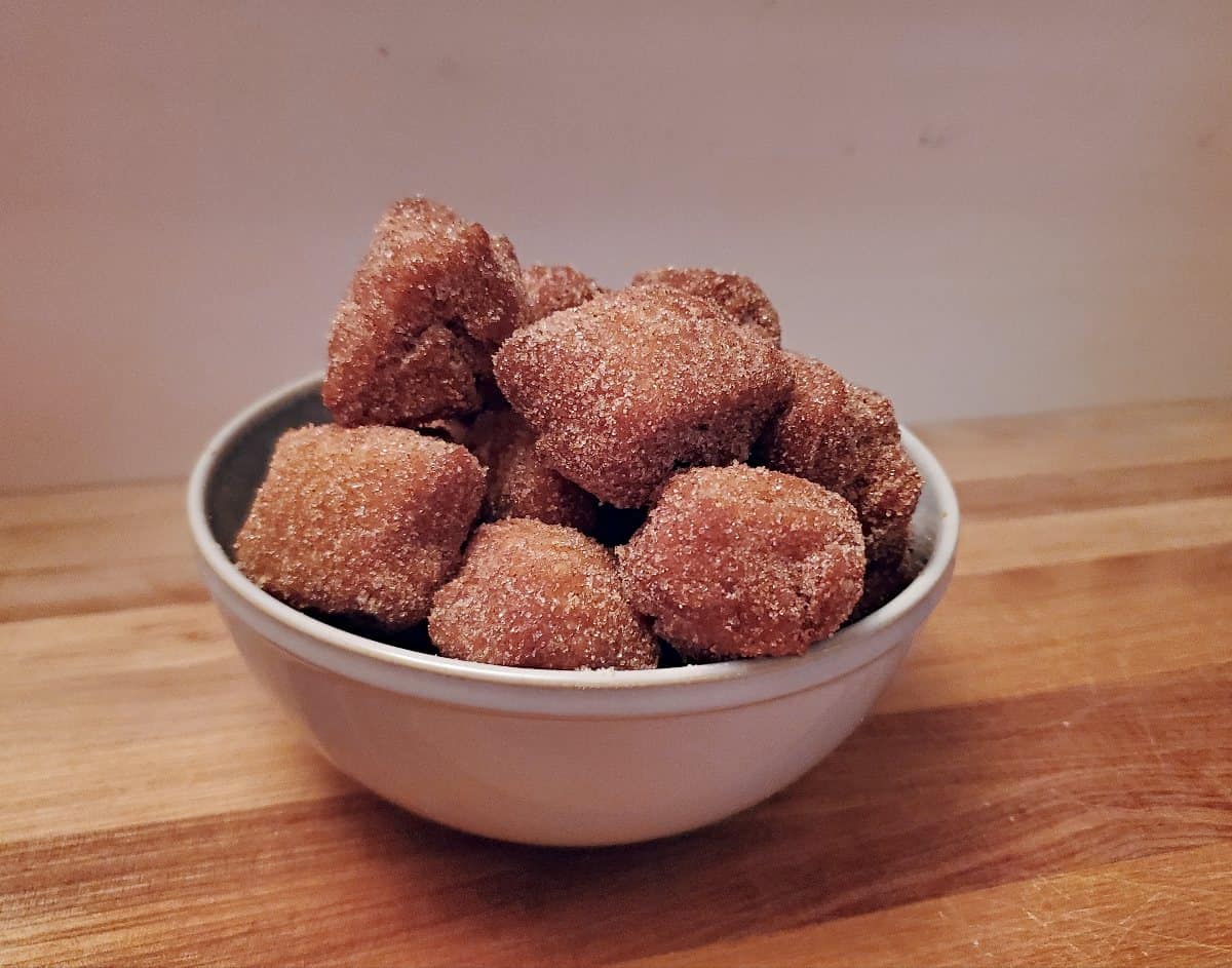 Head on view of pumpkin donut holes in a blue bowl on a wooden table.