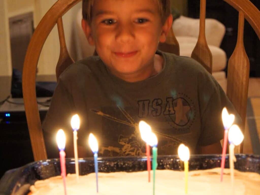 Image shows kid blowing birthday candles on top of cake.