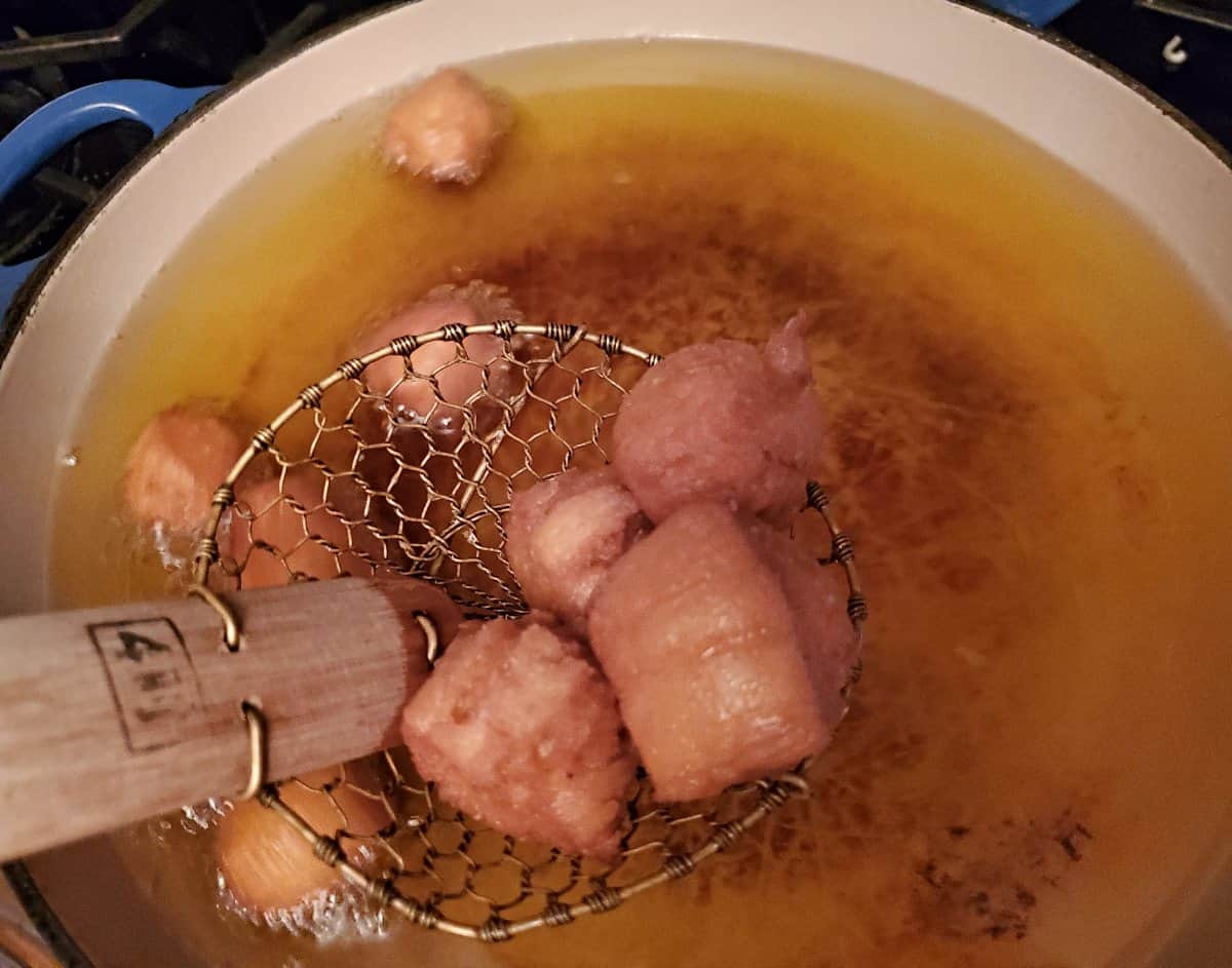 Removing cooked donut holes with a spider tool.
