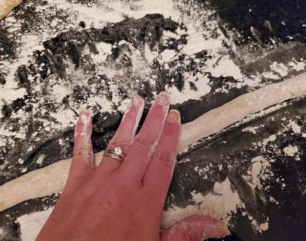 Rolling out dough for pumpkin donuts by hand on a very floured surface.