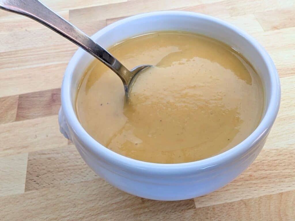 Image shows finished roasted butternut squash soup served in a bowl.