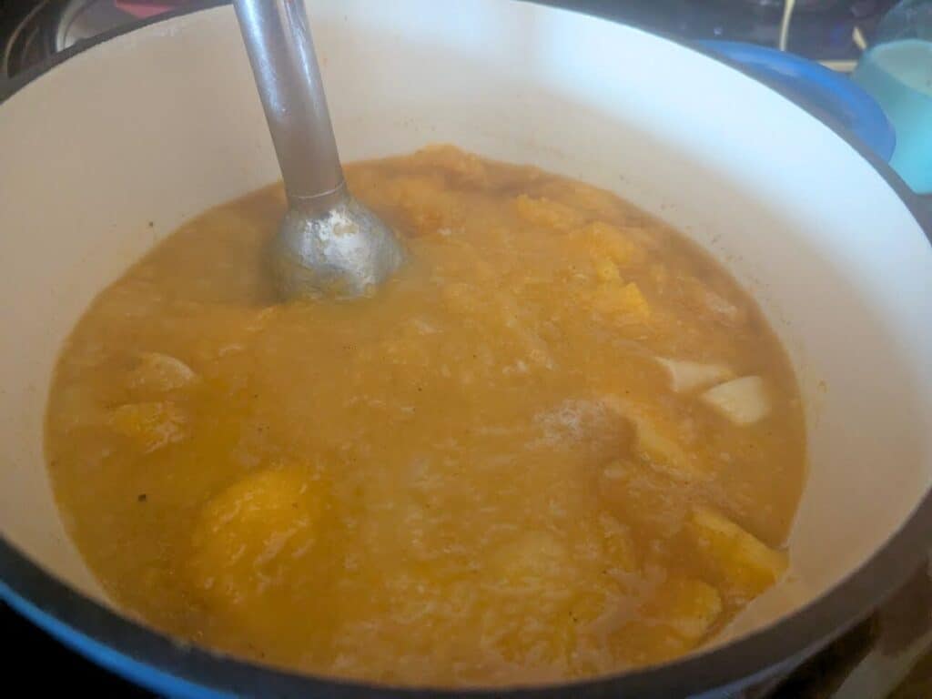 Image shows mixing together the ingredients of roasted butternut squash soup.