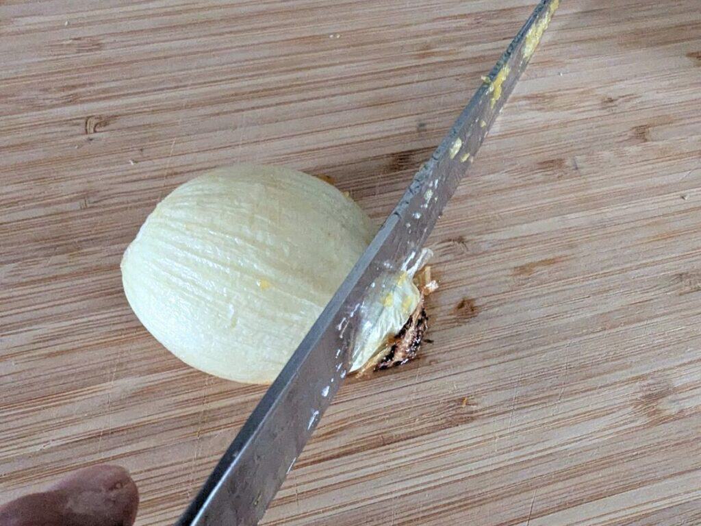 Image shows peeled onion on a chopping board.