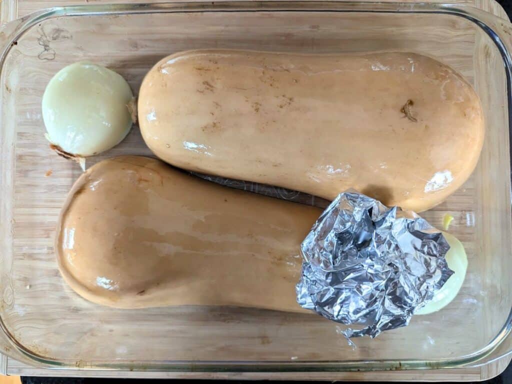 Image shows ready to be roasted butternut squash with onion and garlic.