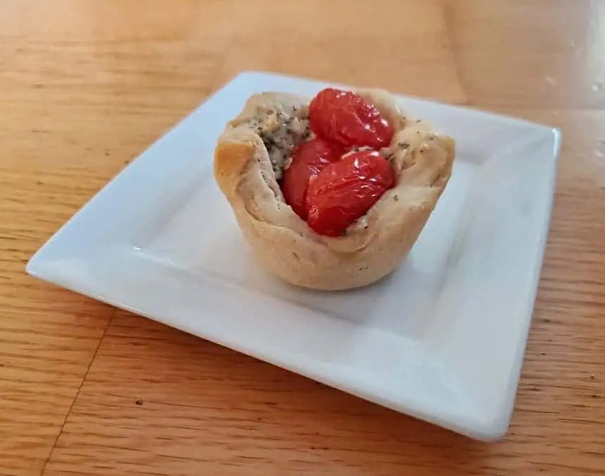 Single tomato basil cup on a white plate