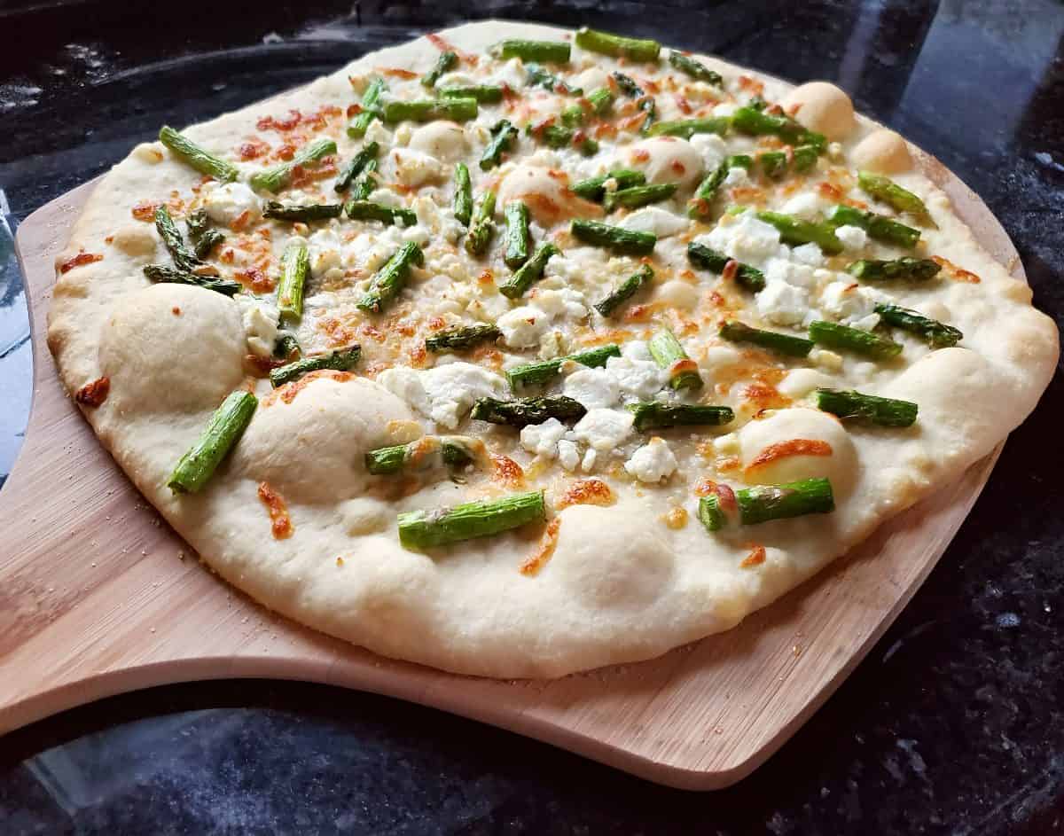 Asparagus goat cheese pizza on a pizza peel.