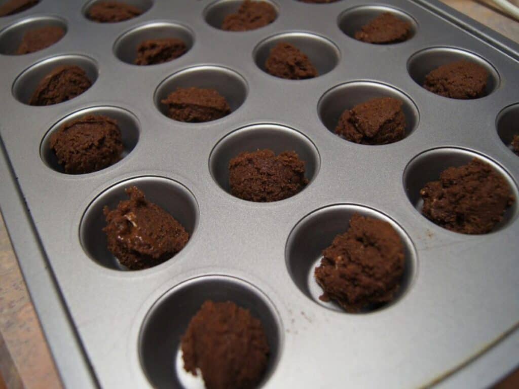 Image shows cherry bliss bites dough in a small muffin tin.