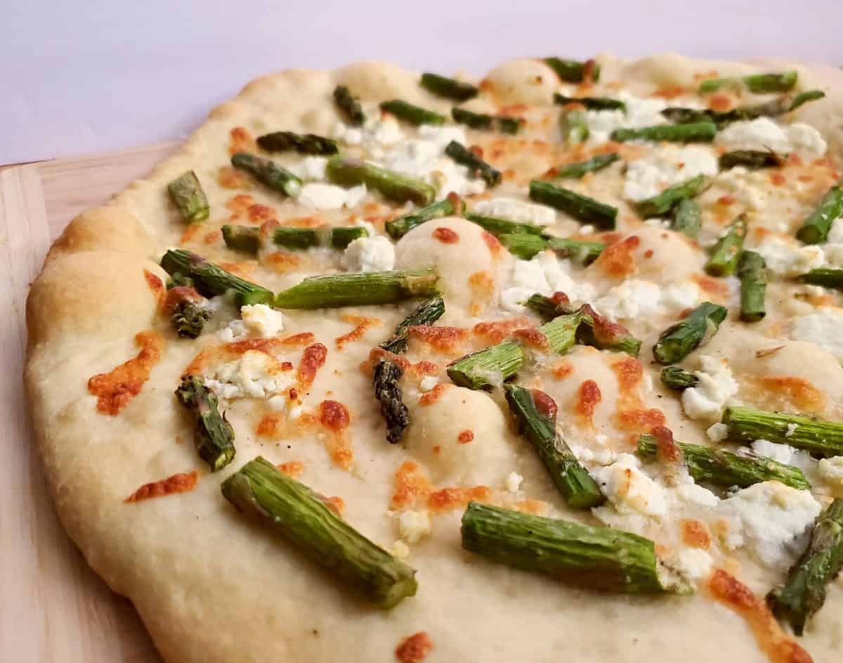 Closeup of an uncut asparagus goat cheese pizza