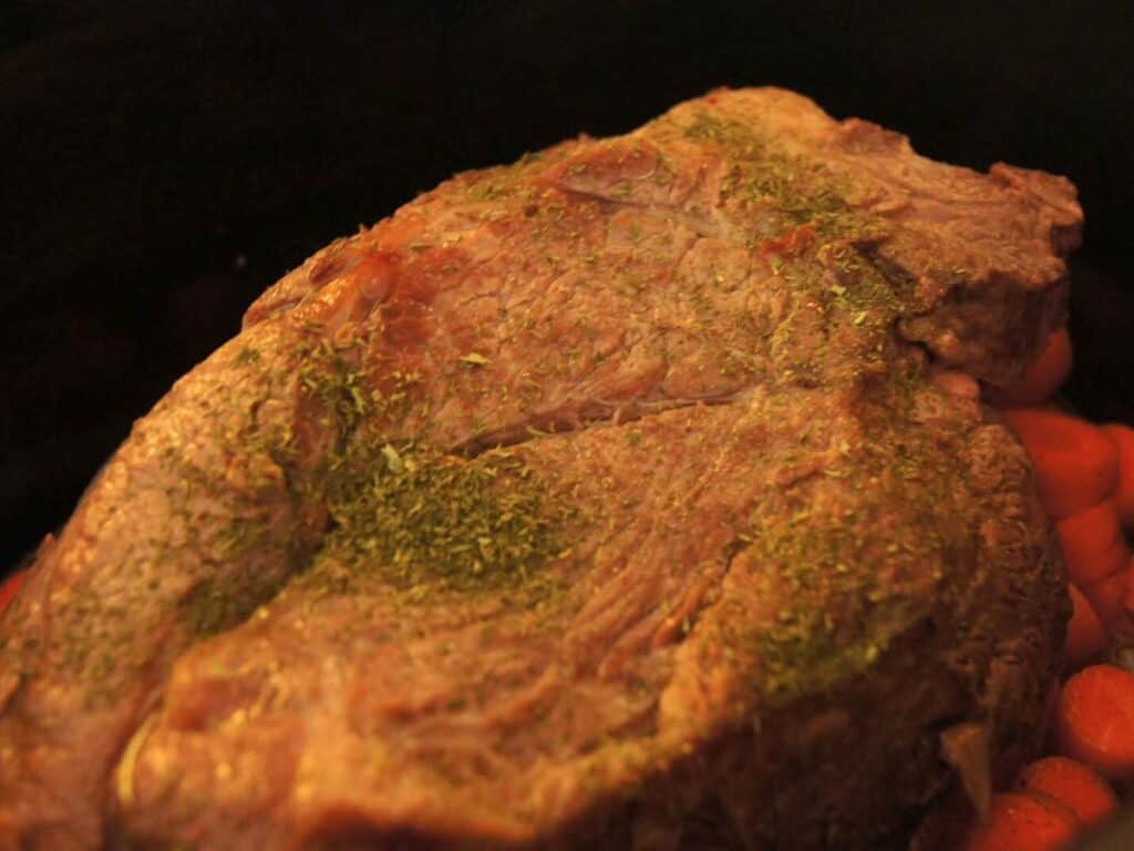 Image shows roast with vegetables in a crock pot.
