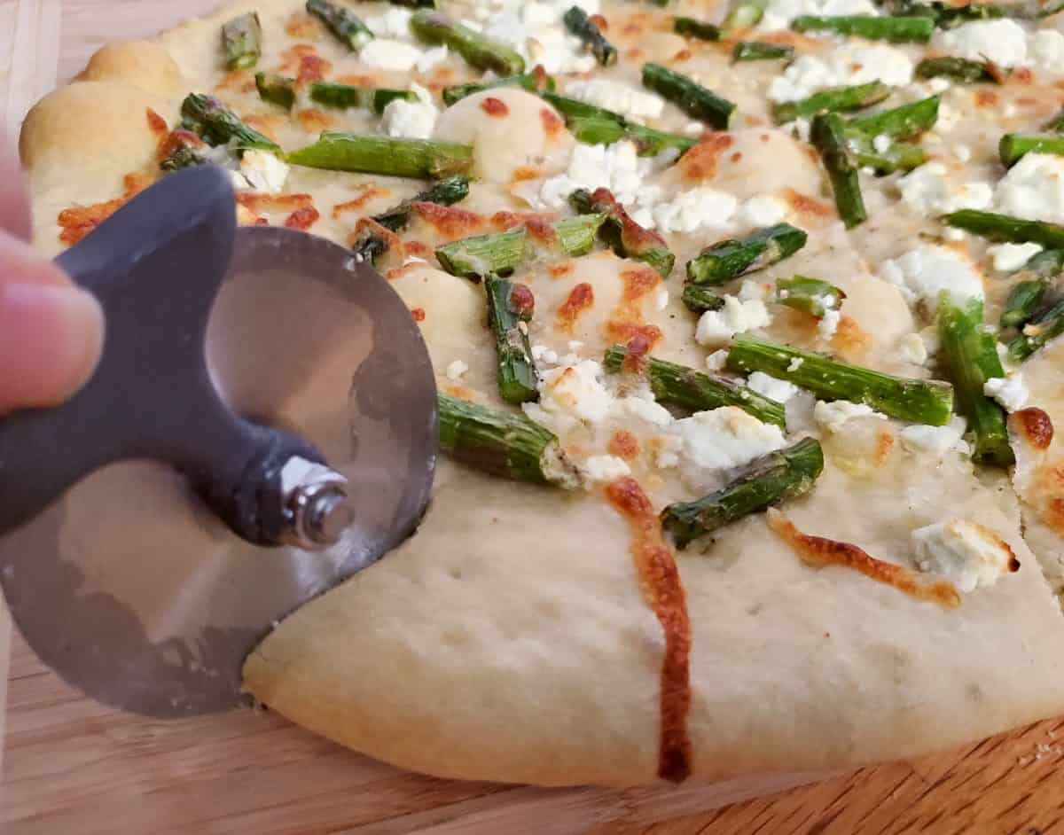 Slicing into an asparagus goat cheese pizza