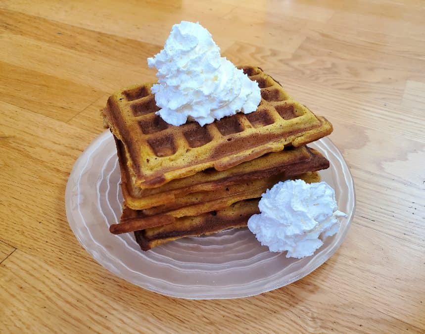 Plate of pumpkin waffles with whipped cream