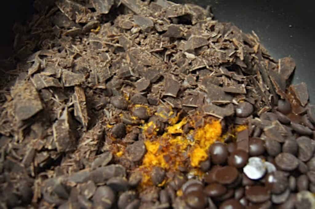 Chopped chocolate with orange zest in a silver bowl.