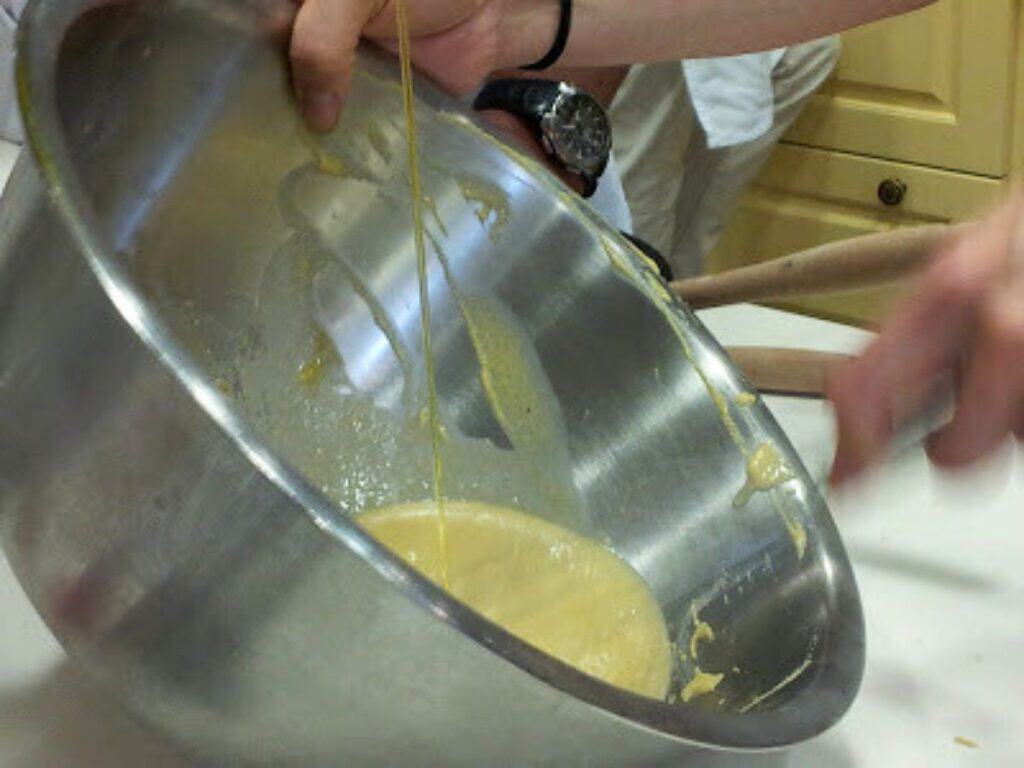 Image shows whisking in the oil for roasted garlic aioli.