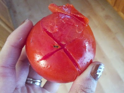 Blanched tomato with the skin starting to peel away.