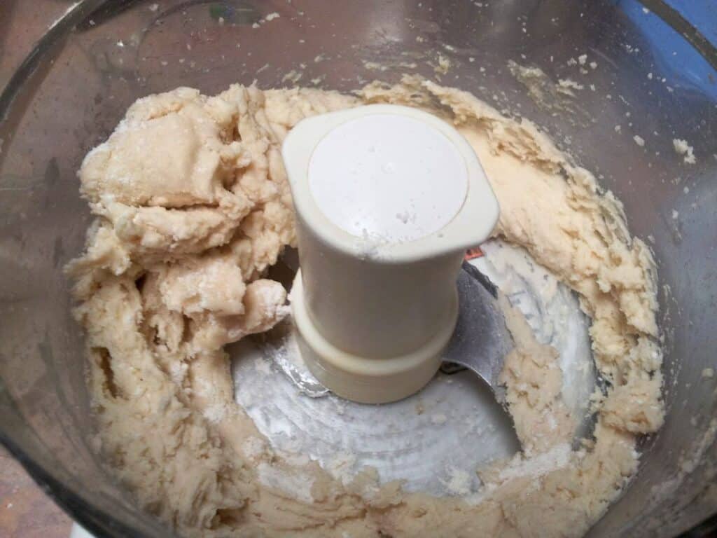 Image shows pie crust pulsed to pea-size bits with liquid ingredients.