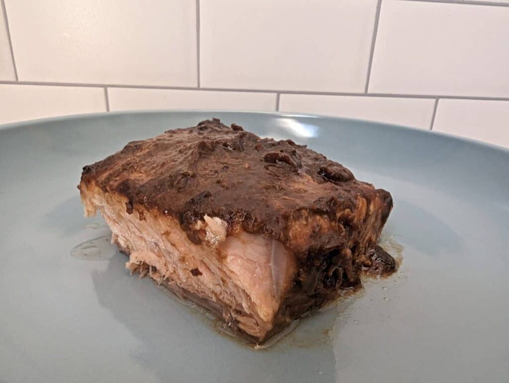 Image shows fillet of salmon on a blue plate with asian glaze.