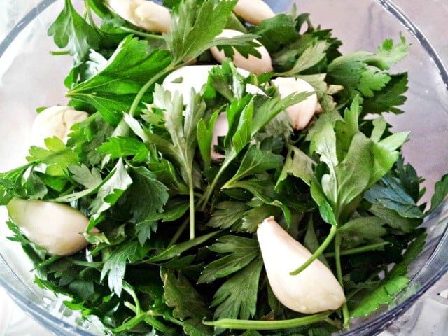 Herbs ready to chop for chimichurri almost fill the food processor bowl