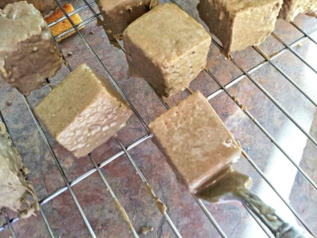 Image shows carefully putting the coated cake squares on a cooling rack.