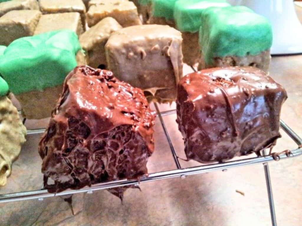 Image shows square-cut cake covered with melted dark chocolate.