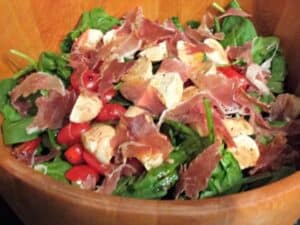 Close up of spinach caprese salad in a wooden bowl.