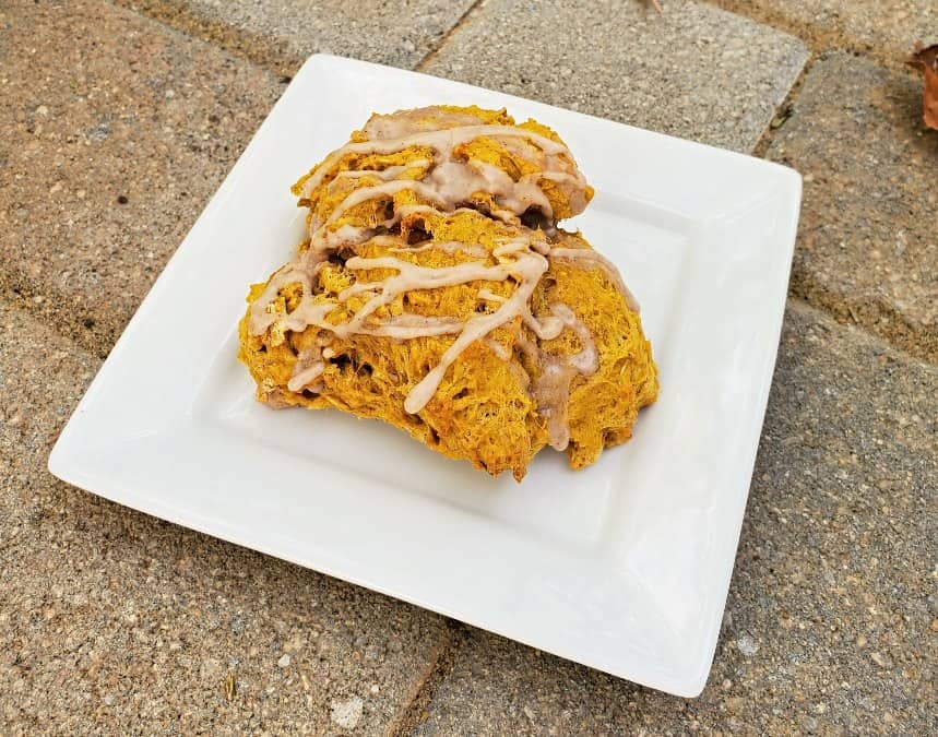 Image shows Three pumpkin scones on a plate with icing.
