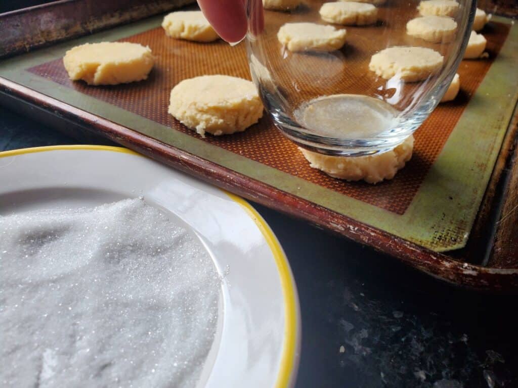 Glass flattening cookies on a cookie sheet.