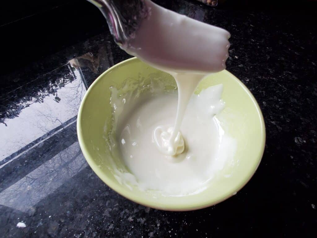 Glaze dripping off a fork into a bowl.