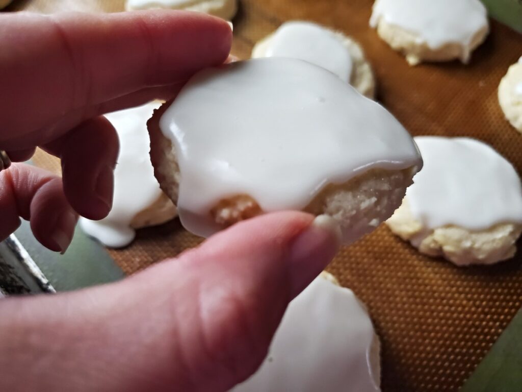 Hand holding a cookie dripping with glaze.