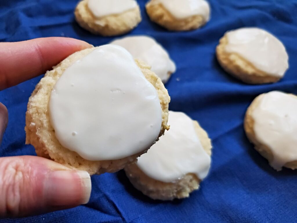 Hand holding a cookie with more in the background.