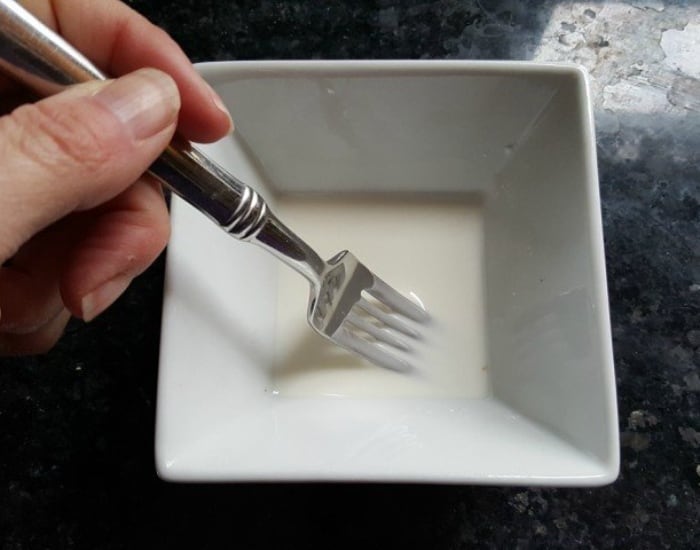 Stirring cornstarch slurry in a small white bowl with a fork.
