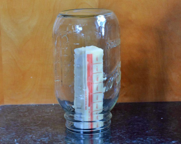 Image shows a stick of butter inside a warm mason jar to soften.