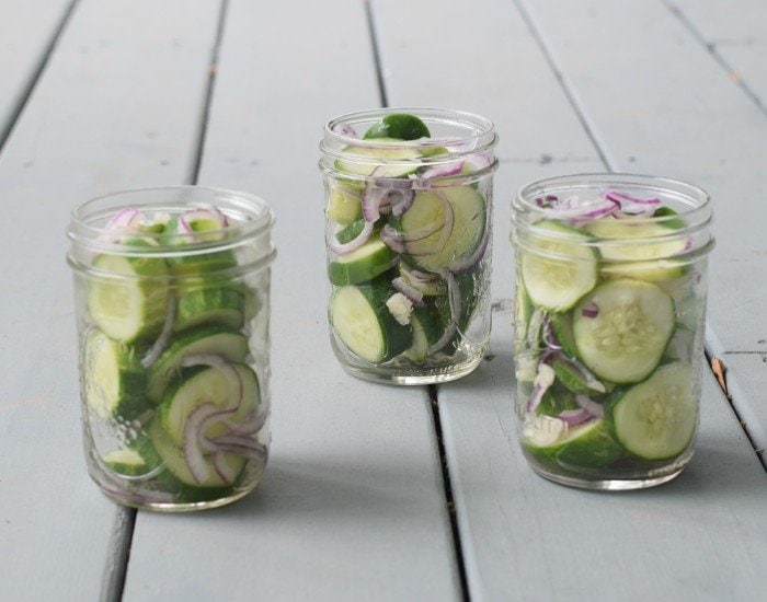 Pack rinsed cucumbers and onions into mason jars as tightly as possible