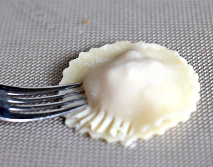 Crimp edges of cheesy chicken empanadas with a fork