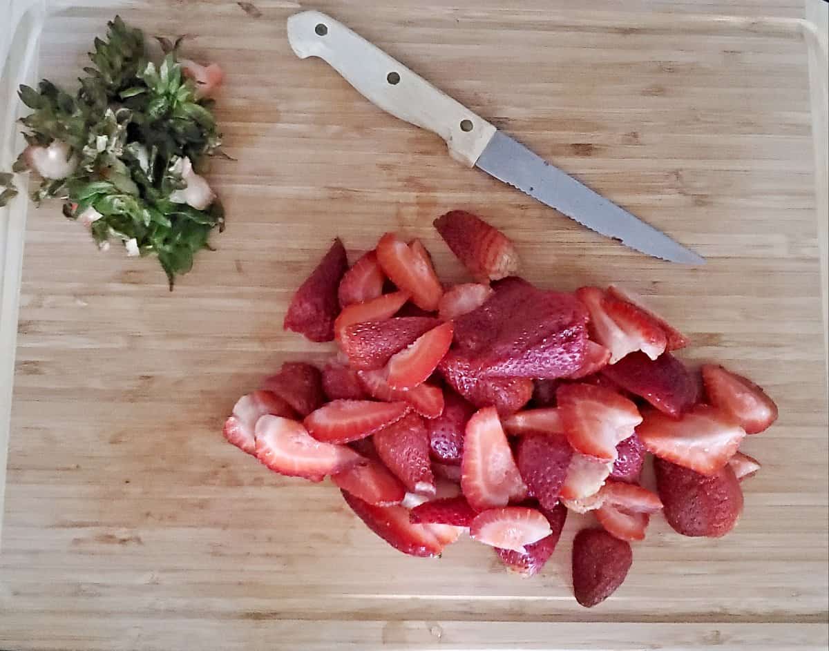 Sliced strawberries on a cutting board.