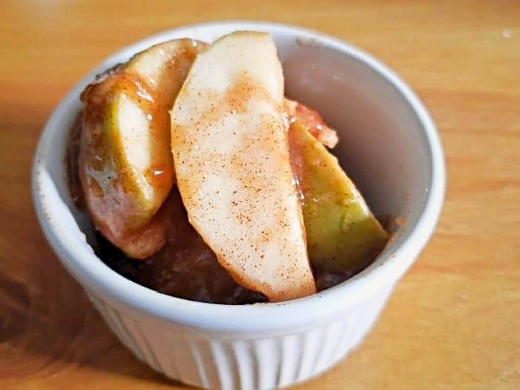 Instant Pot cinnamon apples&mdash;sliced and gently cooked with cinnamon and sauce&mdash;are served in a white ramekin, beautifully presented on a wooden surface.