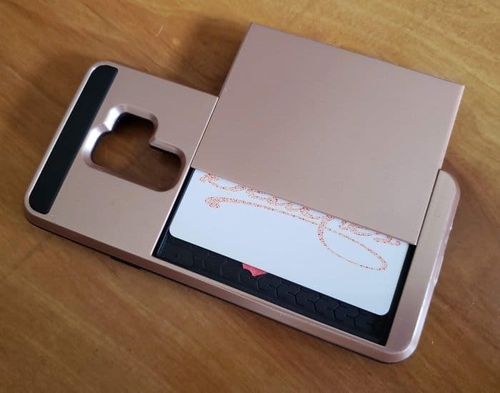 Rose gold cell phone case with a sliding back showing a room key in the card slot.