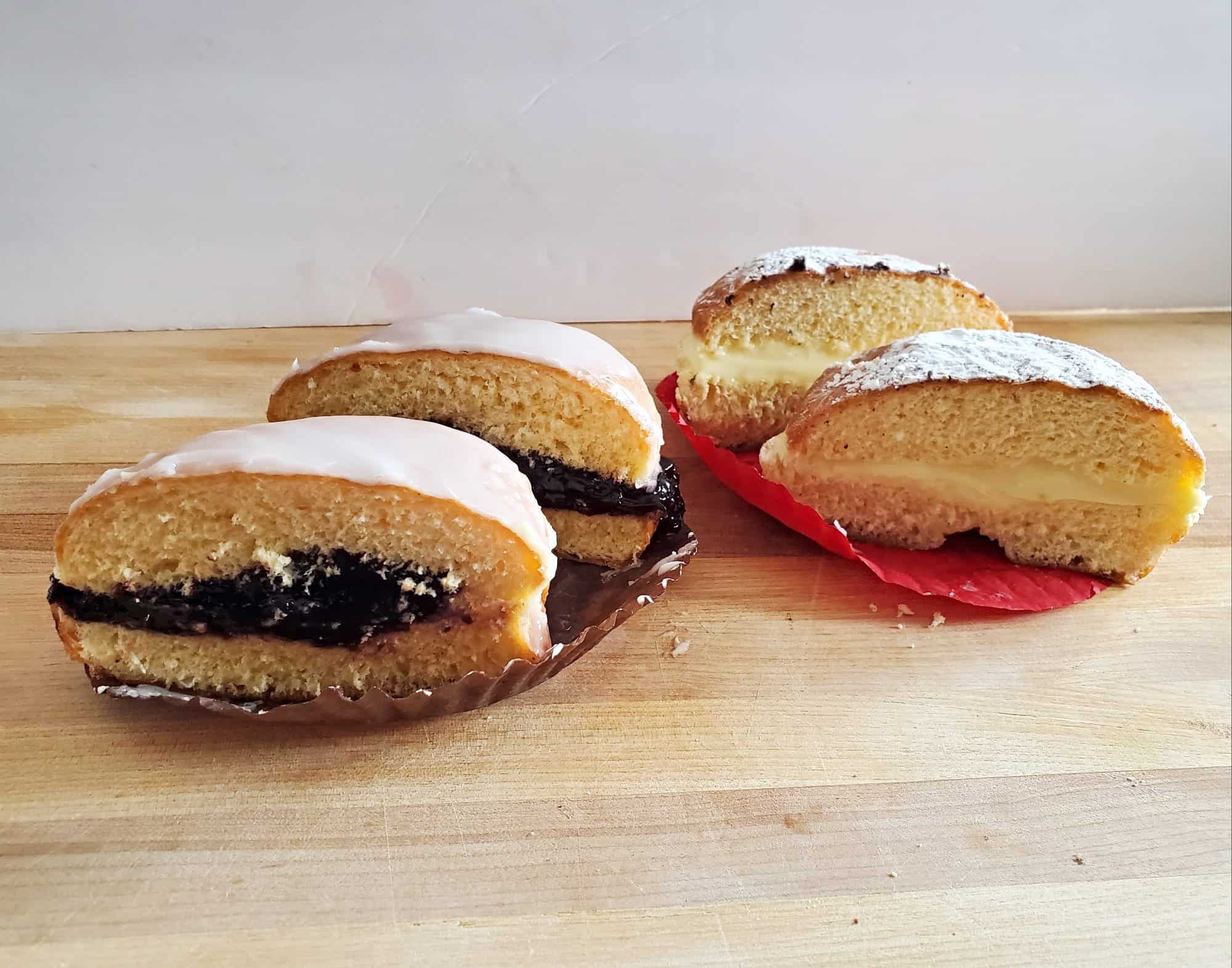 Blueberry and custard paczki from Aracelys Bakery show plenty of filling cut in half sitting on a cutting board.