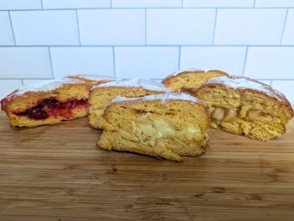 Image shows four paczki flavors on a wooden board from Karina's Bakery in Mundelein.