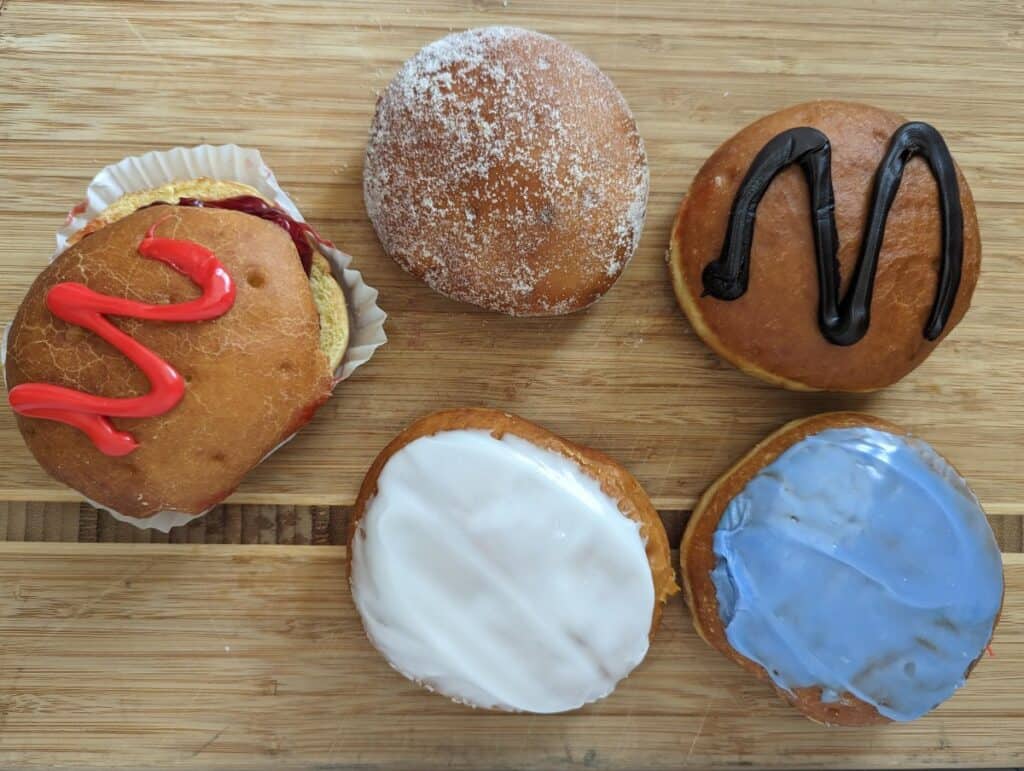 Overhead of five paczki from Chicago Pastry on a wooden board.