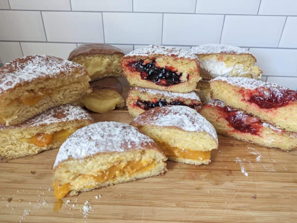 Paczki from Country Style Donuts cut in half sitting on a wooden board.