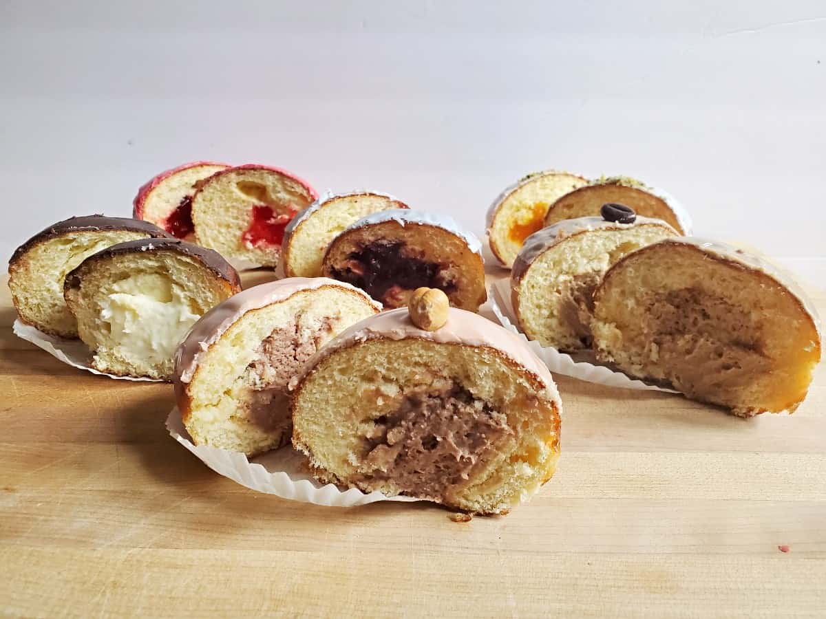 Six Oak Mill Bakery paczki on a board sliced in half to see fillings.