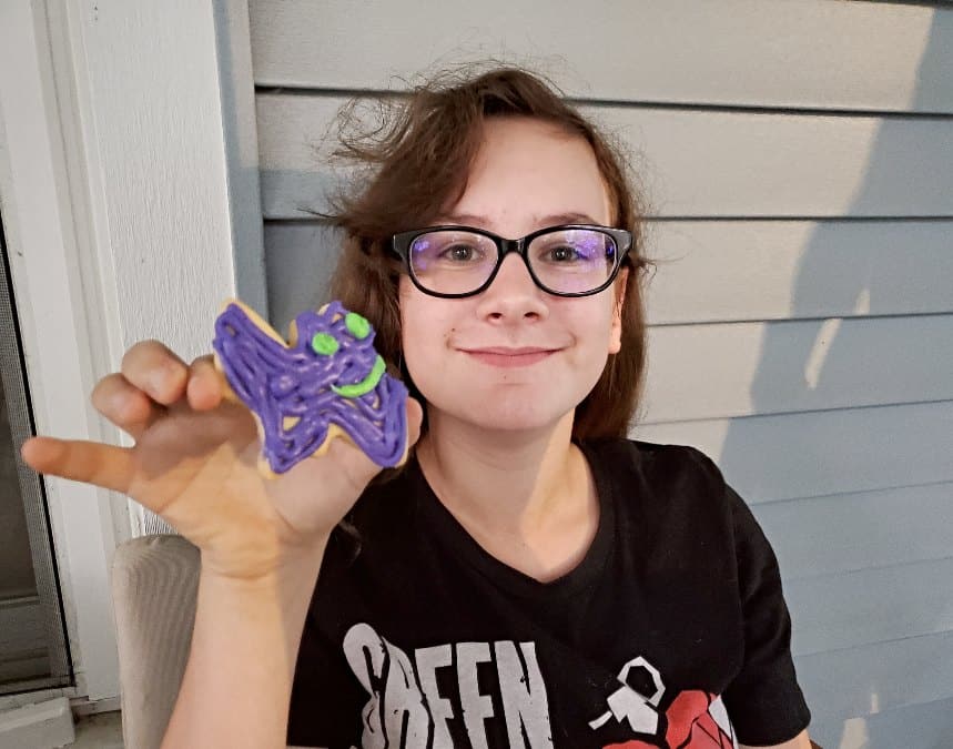 Girl holding a half eaten bat sugar cookie