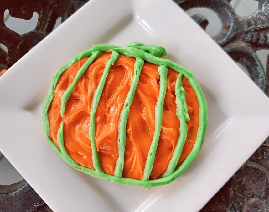 Sugar cookie on a plate decorated to look like a pumpkin
