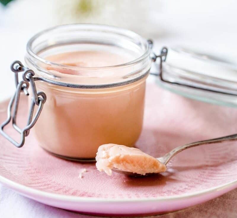 Rhubarb curd in a jar with a spoon next to it.