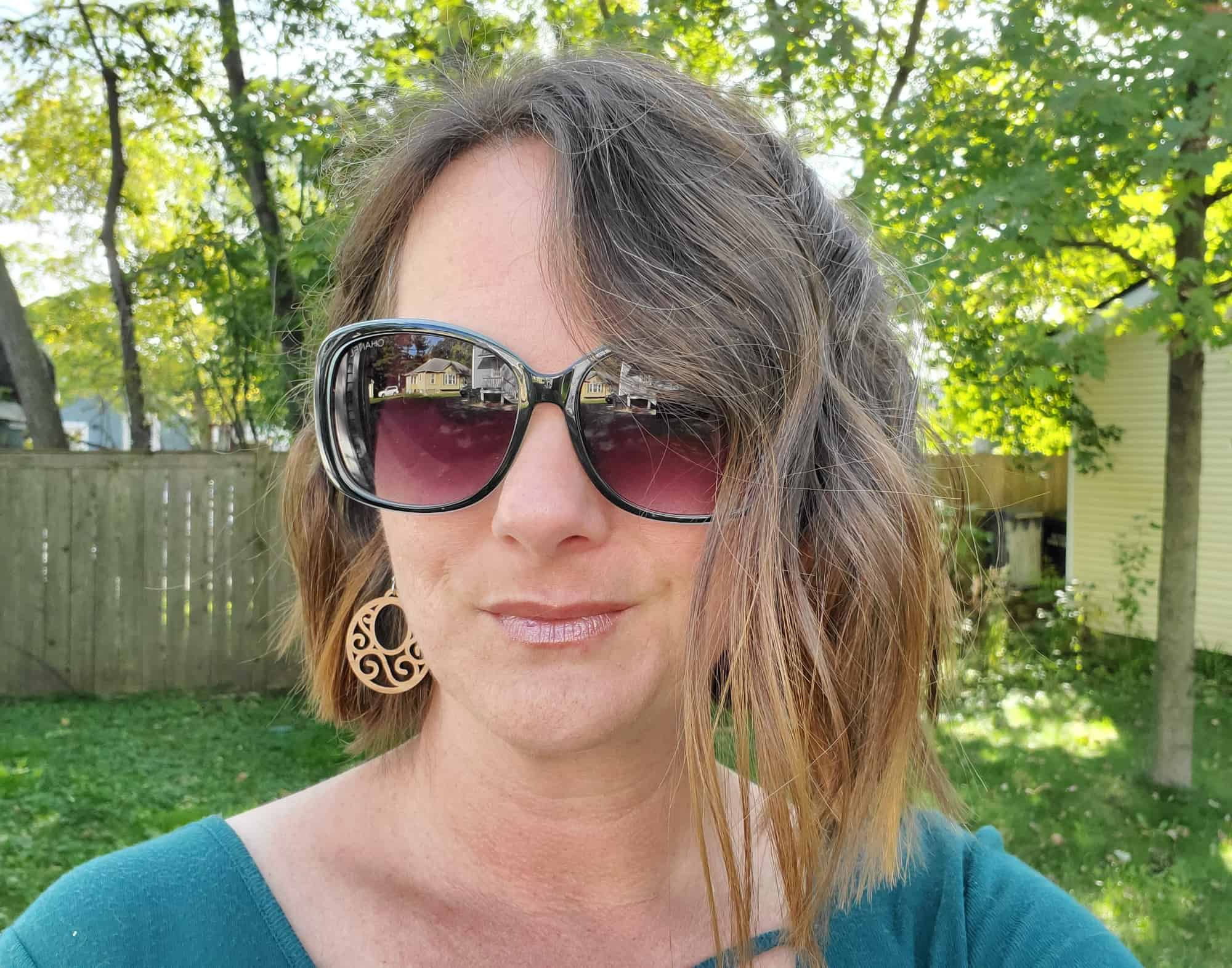 Woman in sunglasses staring confidently into the camera.