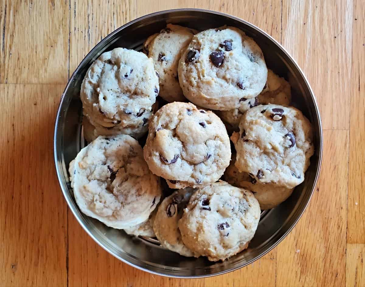 Tin of chocolate chip cookies on a wooden background.