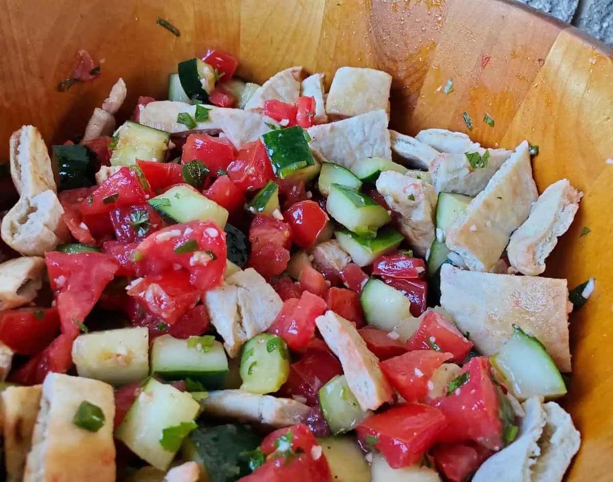 Image shows a Mediterranean Cucumber Tomato Salad in a wooden bowl closeup.