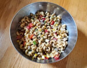 Overhead shot of Greek vegetable pasta salad in a silver bowl.